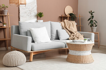 Stylish interior of living room with cozy sofa, pillows, coffee table and plaid