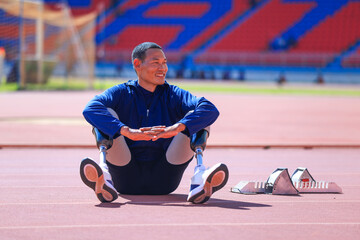 Asian para-athlete with prosthetic blades leg in stadium practicing workout for Paralympic running competition. Amputee sportsman runner practicing running workout. Disabled athlete man sport concept.