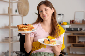 Young woman in wheelchair with tasty waffles and cheese cakes at home