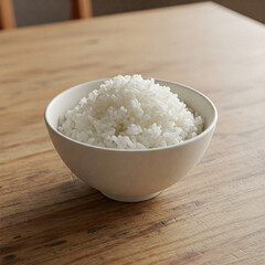 A simple white ceramic bowl, filled with fluffy white rice, sits on a worn wooden table, captured in a close-up shot with soft, natural lighting.