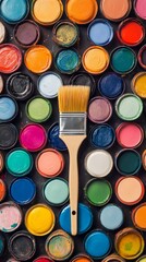 An engaging overhead view of a DIY paint brush surrounded by vibrant sample paint pots, capturing the essence of creativity and the joy of home improvement projects. 