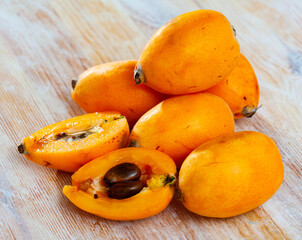 Whole and halved fresh loquat fruit or chinese plum on wooden background