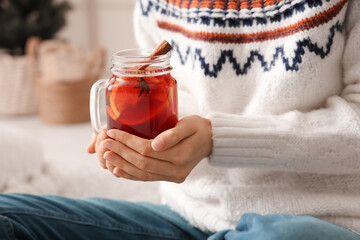 Woman holding mason jar of hot mulled wine at home, closeup