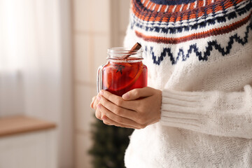Woman holding mason jar of hot mulled wine at home, closeup