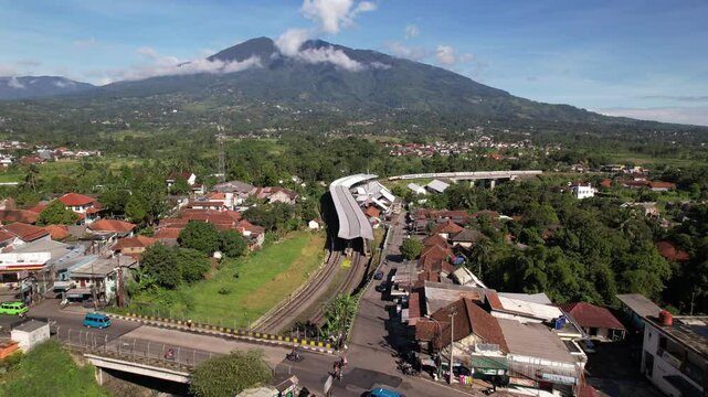 Aerial view of a small town over a lush valley, with a village at the foot of a cloud-covered Mount Salak in Bogor. A perfect blend of nature and infrastructure in Indonesia&rsquo;s highlands