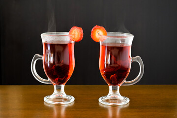 Hot red beverage with steam in elegant glasses