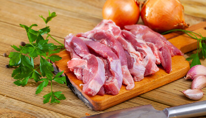 Home cooking. Pieces of fresh raw turkey thigh on bone and condiments prepared for roasting on wooden table..
