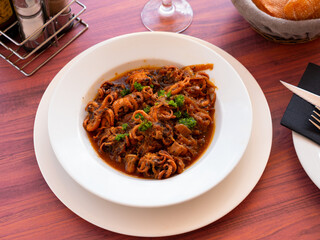 Popular dish of Spanish cuisine is octopus with onions, stewed in sauce