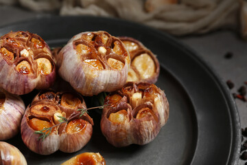 Plate with baked garlic and thyme, closeup