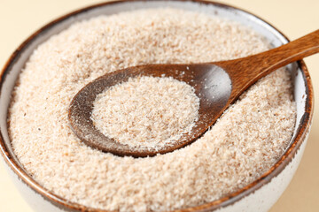 Bowl with psyllium husk powder on beige background, closeup