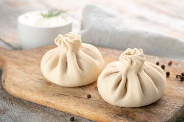 Chinese raw dumplings or Georgian khinkali on a wooden cutting board