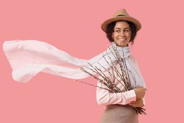 Beautiful young African-American woman with pussy willow branches on pink background