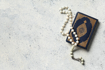 Koran with tasbih on white grunge background. Ramadan celebration