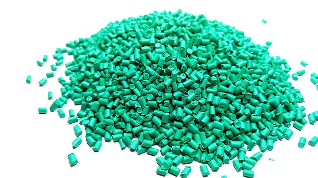 Green masterbatch granules are poured into a white background, suitable for industrial plastic manufacturing company videography design