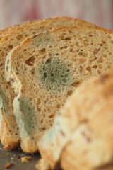 Moldy bread slices displayed on a wooden table in natural light