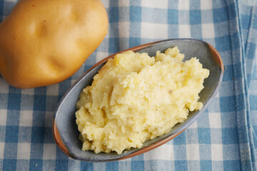 Creamy mashed potatoes served with whole potato on checkered cloth