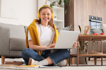 Teenage girl in headphones with laptop working online on floor at home