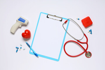 Blank clipboard with stethoscope, pills and infrared thermometer on white background. World Health Day