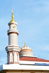 A beautiful mosque with an elegant minaret and dome under a clear blue sky. The intricate Islamic architecture and golden crescent create a serene spiritual atmosphere, symbolizing faith and devotion.