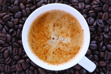 エスプレッソに牛乳をたっぷり入れたコーヒー、カフェ・ラッテと、深煎りしたコーヒー豆
