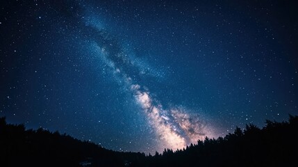Fototapeta premium A person lying on the grass, gazing at the Milky Way in a dark night sky.