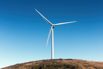 Fototapeta premium solitary wind turbine stands on hilltop against clear blue sky blades slowly turning symbolizing renewable energy innovation