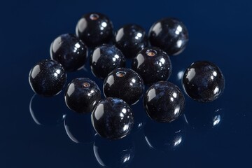 Several glistening dark blue fruits are scattered upon a reflective surface
