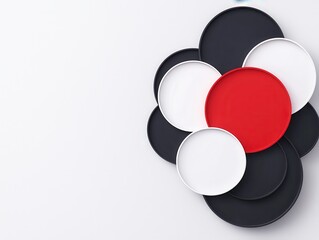 Obraz premium A modern arrangement of circular plates in black, white, and red, creating a stylish, minimalist design on a light background.