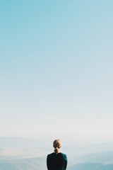 person gazing at vast open landscape from high vantage point symbolizing hope and potential with ample sky above and