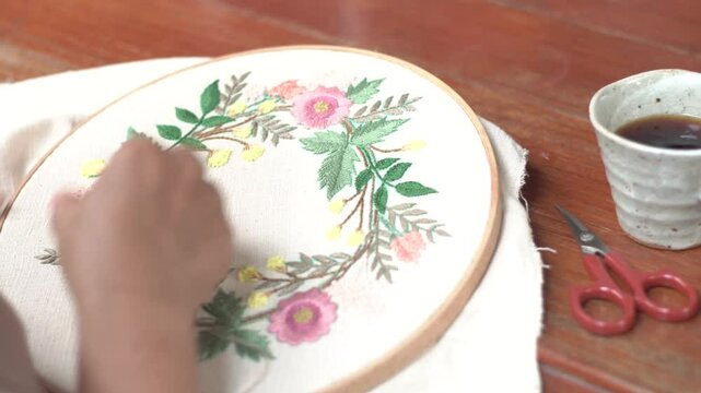 Beautiful embroidery flowers on cotton fabric. Product of needlework on a piece of embroidery. Needlework is decorative sewing and textile arts handicrafts. How to stitch embroider flowers on clothes.