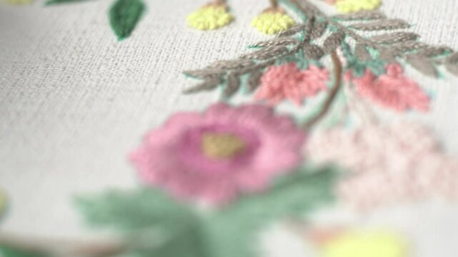 Beautiful embroidery flowers on cotton fabric. Product of needlework on a piece of embroidery. Needlework is decorative sewing and textile arts handicrafts. How to stitch embroider flowers on clothes.