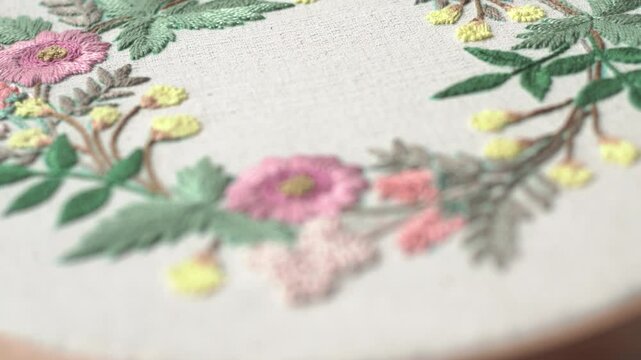 Beautiful embroidery flowers on cotton fabric. Product of needlework on a piece of embroidery. Needlework is decorative sewing and textile arts handicrafts. How to stitch embroider flowers on clothes.