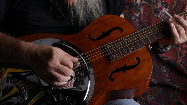 Male musician hand play Vintage Resonator acoustic dobro blues slide guitar.