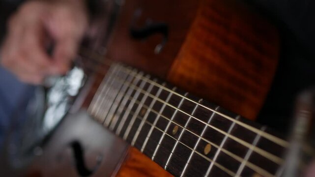 Male musician hand play Vintage Resonator acoustic dobro blues slide guitar.