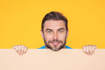 Handsome happy man holding empty board on studio. Smiling guy showing blank signboard with...