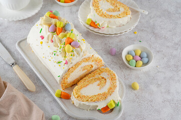 Easter carrot roll cake with cream cheese frosting, decorated chocolate eggs, jellied carrots and...