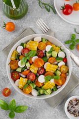 Sweet corn salad with arugula, tomatoes, cucumber, red onion and mozzarella. Healthy food. Top view.