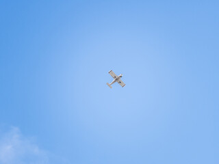 Small ultralight airplane with overhead wing and single propeller flying in sunset sky.