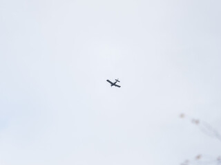 Small ultralight airplane with overhead wing and single propeller flying in sunset sky.