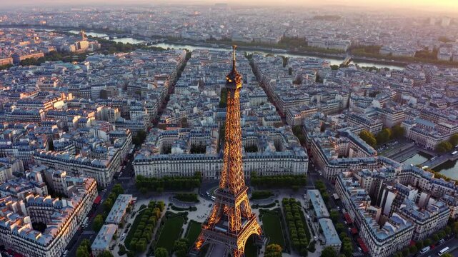 Aerial video captures the Eiffel Tower at sunset, showcasing Paris's sprawling cityscape from a high angle, highlighting urban elegance.