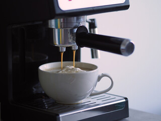 White cup drop image of iced cream coffee from machines percolator. Streams of coffee pour to drink. Drink flowing cappuccino cup that is prepar service Coffee home atmosphere warm of espresso pouring