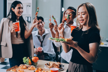 Asian office colleagues and friends enjoy a daytime BBQ with pizza and beer, celebrating Halloween and cheering for their favorite soccer team, creating a lively atmosphere filled with joy.