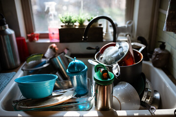 Sunlit kitchen sink full of dirty dishes