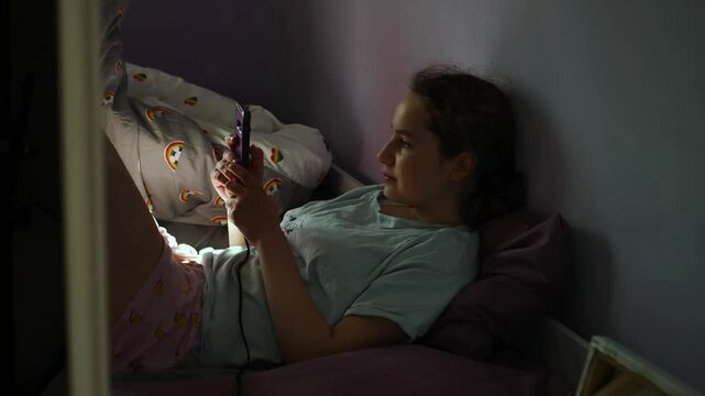 Teen girl using her smartphone, watching video online at home