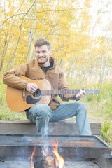 Fototapeta premium man plays guitar around campfire
