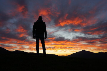Obraz premium man in the mountain looking at the sunset in the summer