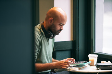 A man with headphones is using a computer tablet
