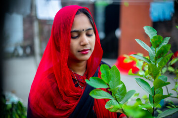 A young Asian woman poses in a red dress amidst the greenery of nature. Fashion model portrait.