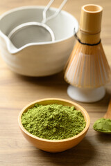 Matcha green tea powder with tea bowl and chasen on wooden background