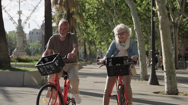 Happy senior couple riding bikes in barcelona, slow motion montage